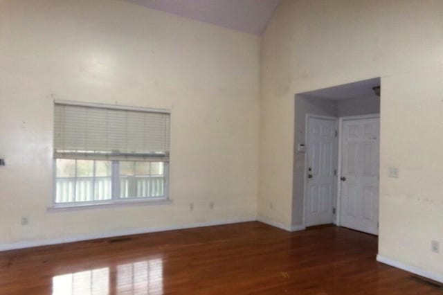 spare room with lofted ceiling and dark wood-type flooring