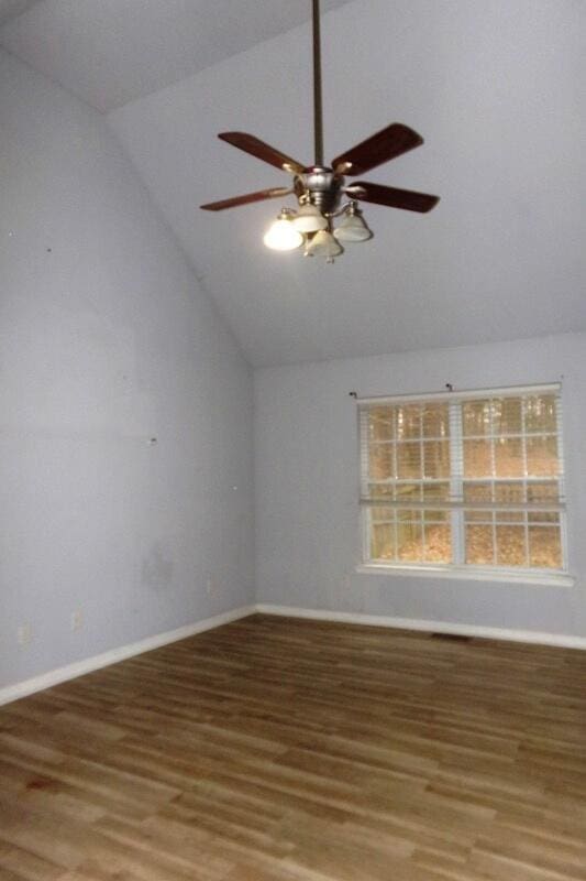 spare room with hardwood / wood-style flooring, vaulted ceiling, and ceiling fan