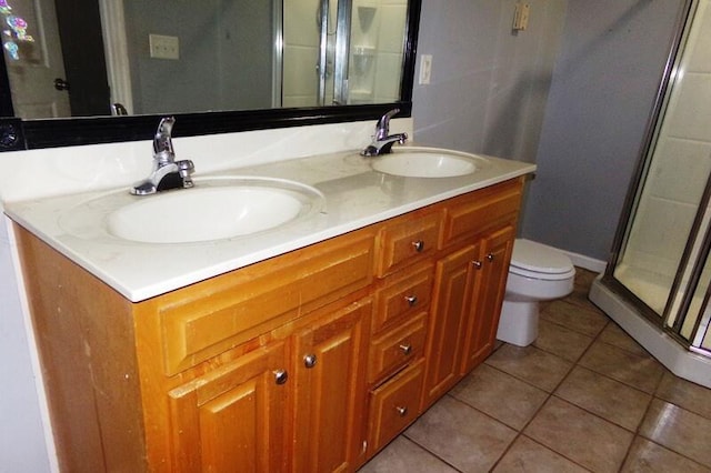 bathroom featuring vanity, toilet, a shower with shower door, and tile patterned flooring