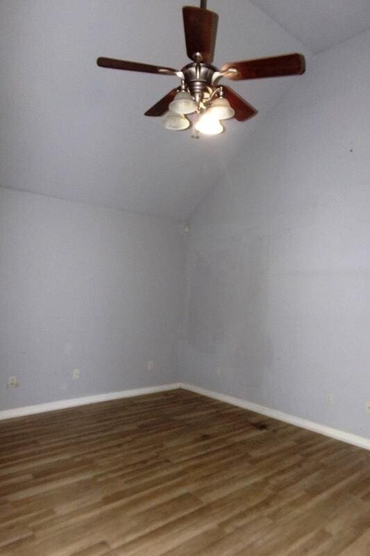 spare room featuring dark wood-type flooring and vaulted ceiling