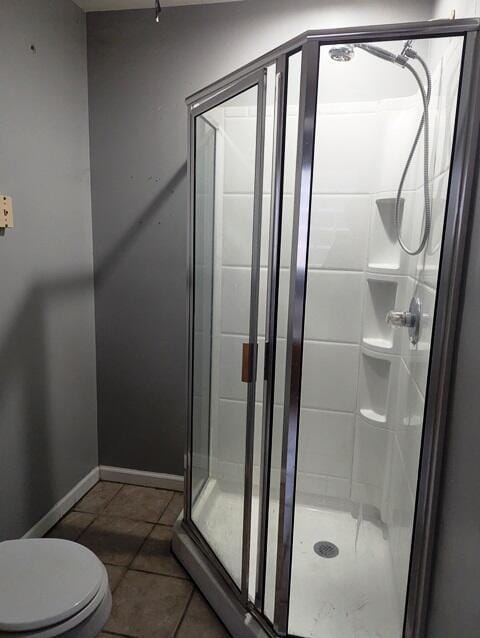 bathroom featuring tile patterned floors, toilet, and a shower with door