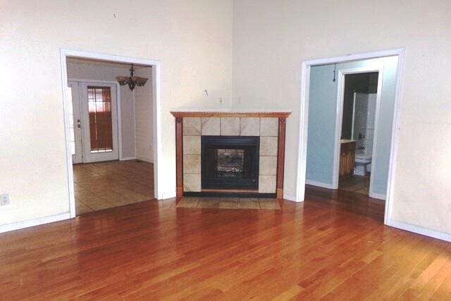 unfurnished living room with hardwood / wood-style flooring and a tile fireplace