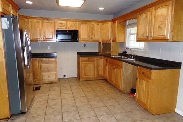 kitchen featuring stainless steel refrigerator with ice dispenser, sink, and light tile patterned floors