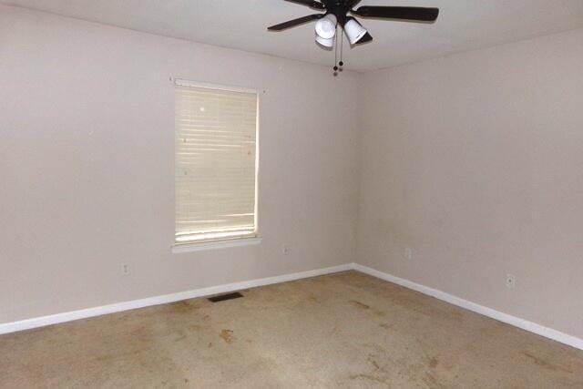 unfurnished room with ceiling fan and carpet