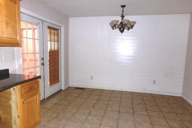 unfurnished dining area featuring french doors and an inviting chandelier