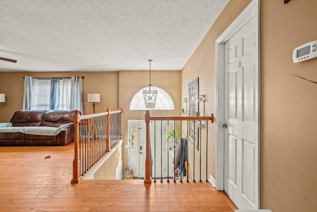 entrance foyer featuring hardwood / wood-style flooring, a textured ceiling, and a notable chandelier