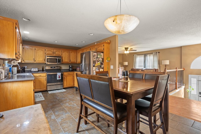 kitchen featuring sink, decorative light fixtures, a textured ceiling, appliances with stainless steel finishes, and ceiling fan