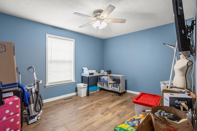 misc room with ceiling fan, wood-type flooring, and a textured ceiling