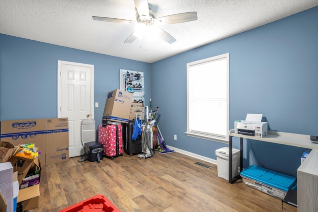 miscellaneous room featuring ceiling fan, wood-type flooring, and a textured ceiling