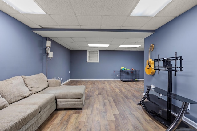 living room featuring wood-type flooring and a drop ceiling