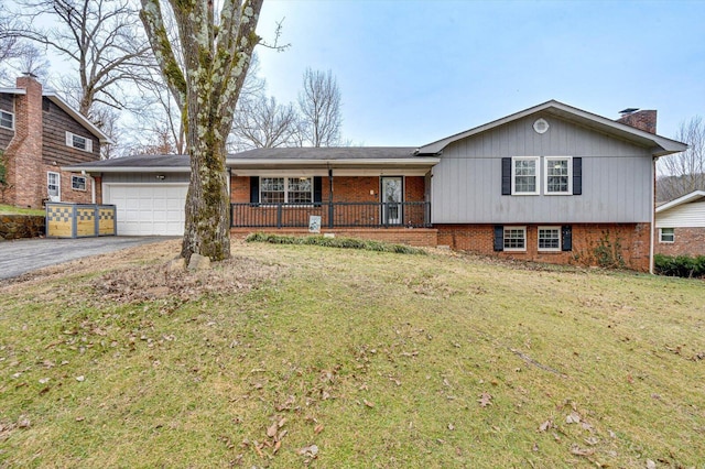 split level home featuring a garage, covered porch, and a front lawn