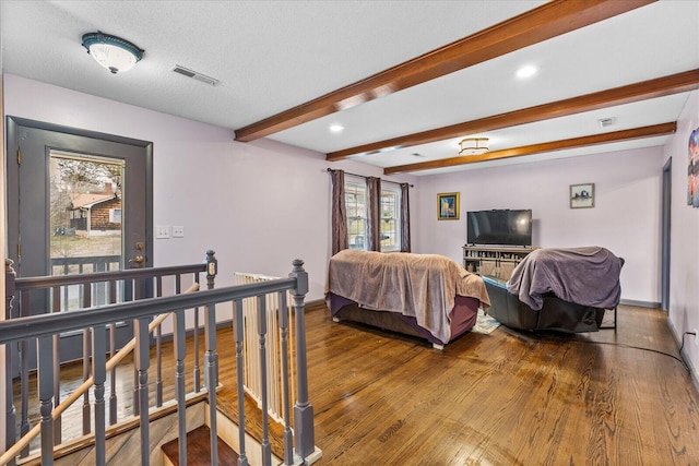 bedroom featuring beamed ceiling, wood-type flooring, and a textured ceiling