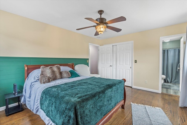 bedroom with ensuite bathroom, dark wood-type flooring, ceiling fan, and a closet