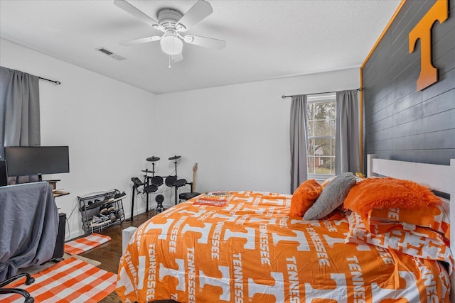 bedroom with ceiling fan, dark hardwood / wood-style flooring, a textured ceiling, and wood walls