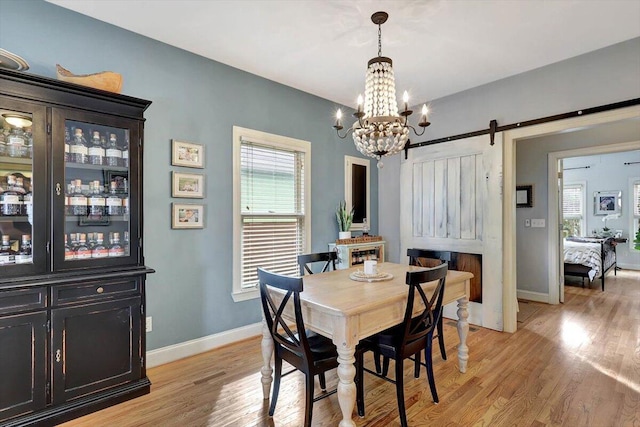 dining room featuring a barn door, an inviting chandelier, and light hardwood / wood-style flooring