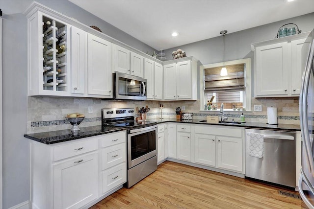 kitchen featuring sink, hanging light fixtures, light hardwood / wood-style flooring, appliances with stainless steel finishes, and white cabinets