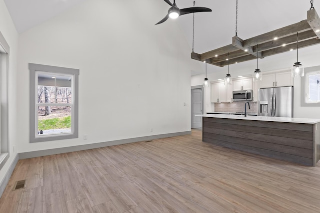 kitchen with high vaulted ceiling, appliances with stainless steel finishes, light countertops, and visible vents