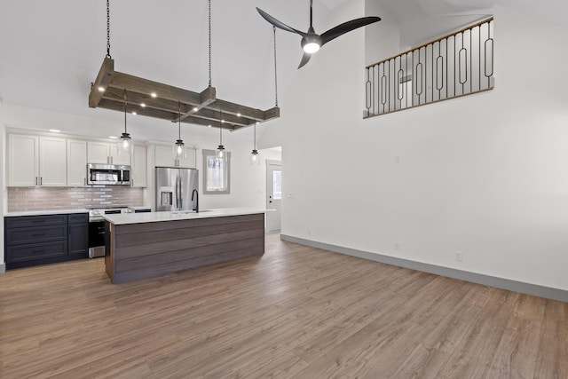 kitchen with stainless steel appliances, light countertops, high vaulted ceiling, and a ceiling fan