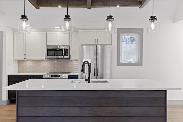 kitchen featuring light countertops, appliances with stainless steel finishes, a sink, and light wood-style floors