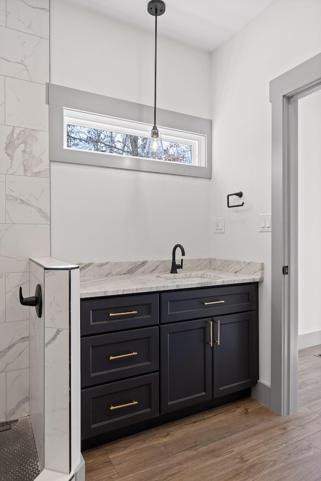 bar featuring light wood-style floors, a sink, and hanging light fixtures