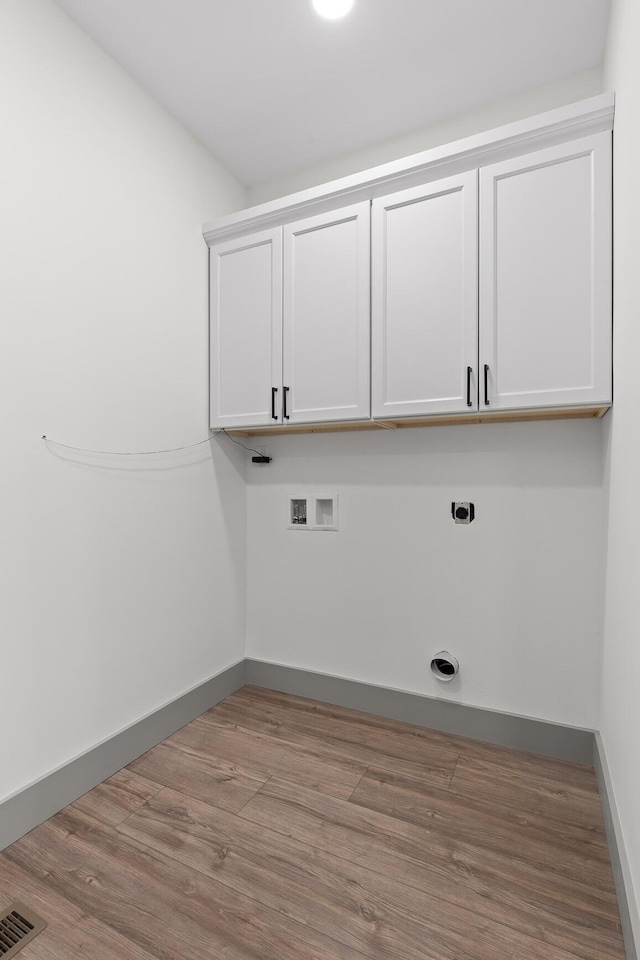 washroom featuring cabinet space, visible vents, wood finished floors, hookup for a washing machine, and hookup for an electric dryer