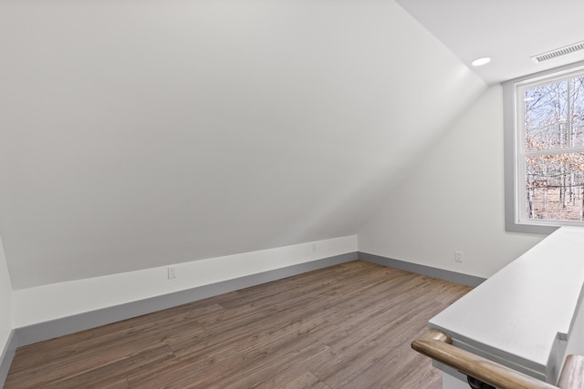 additional living space featuring lofted ceiling, visible vents, baseboards, and wood finished floors