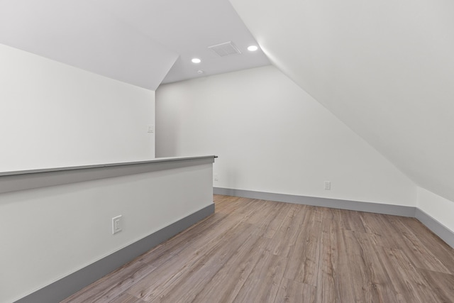 additional living space with lofted ceiling, recessed lighting, wood finished floors, visible vents, and baseboards