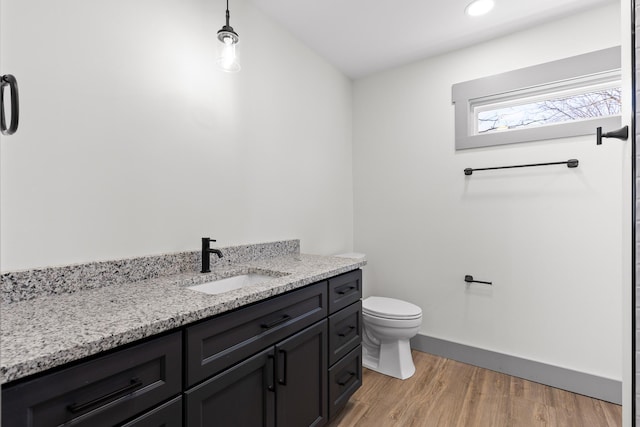 bathroom featuring toilet, baseboards, wood finished floors, and vanity