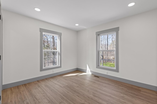 empty room with wood finished floors, a wealth of natural light, and recessed lighting