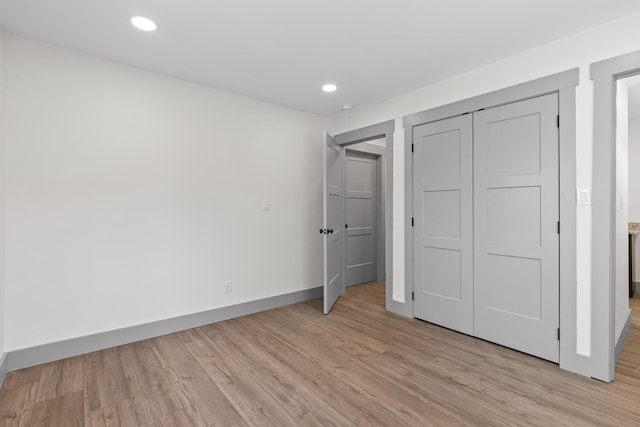 unfurnished bedroom featuring baseboards, a closet, light wood-type flooring, and recessed lighting