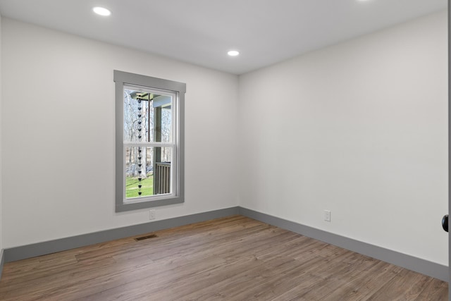 spare room featuring baseboards, wood finished floors, visible vents, and recessed lighting