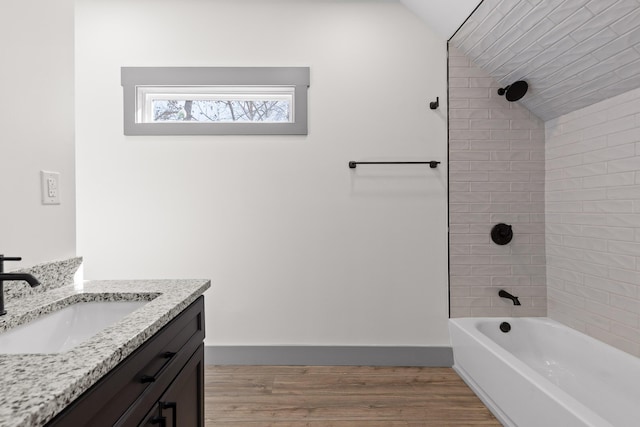 bathroom with lofted ceiling, wood finished floors, vanity, and baseboards