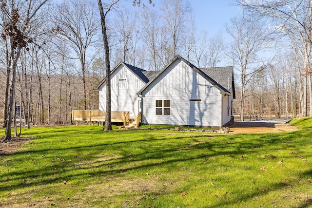 view of home's exterior featuring a deck, a shingled roof, a lawn, and board and batten siding