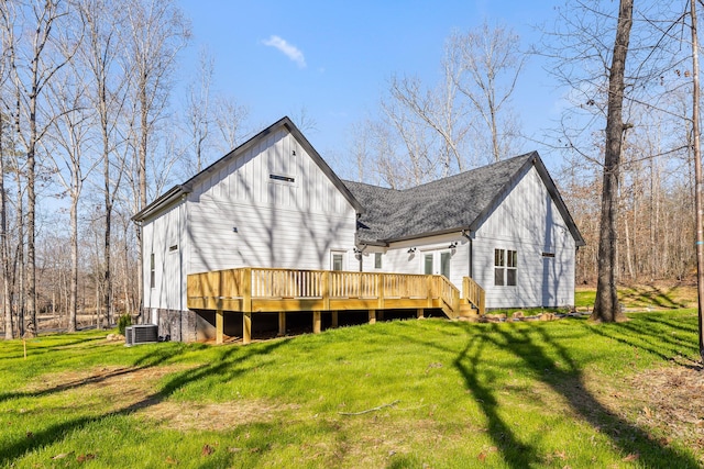 back of property featuring a shingled roof, cooling unit, a deck, and a lawn