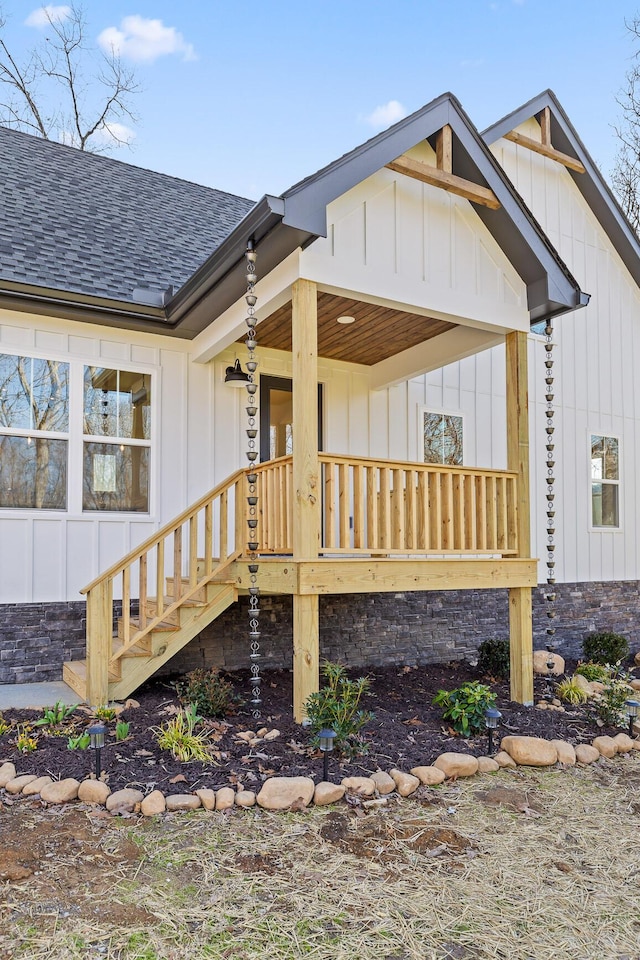 entrance to property featuring covered porch, a shingled roof, and board and batten siding