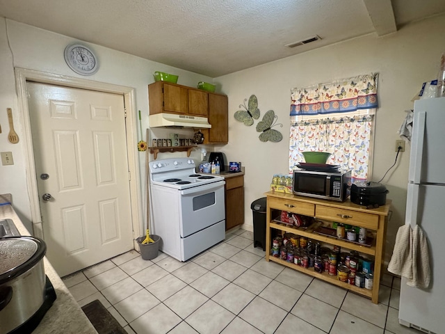 kitchen with light tile patterned floors, a textured ceiling, and white appliances