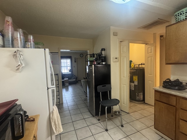 kitchen featuring light tile patterned floors, stainless steel fridge, water heater, white refrigerator, and a textured ceiling