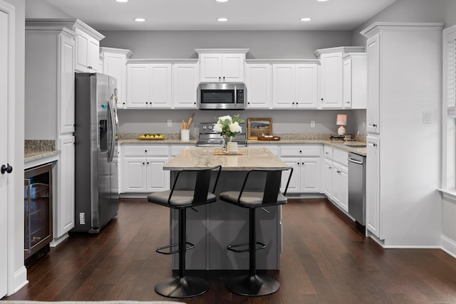 kitchen with white cabinetry, appliances with stainless steel finishes, a center island, and wine cooler