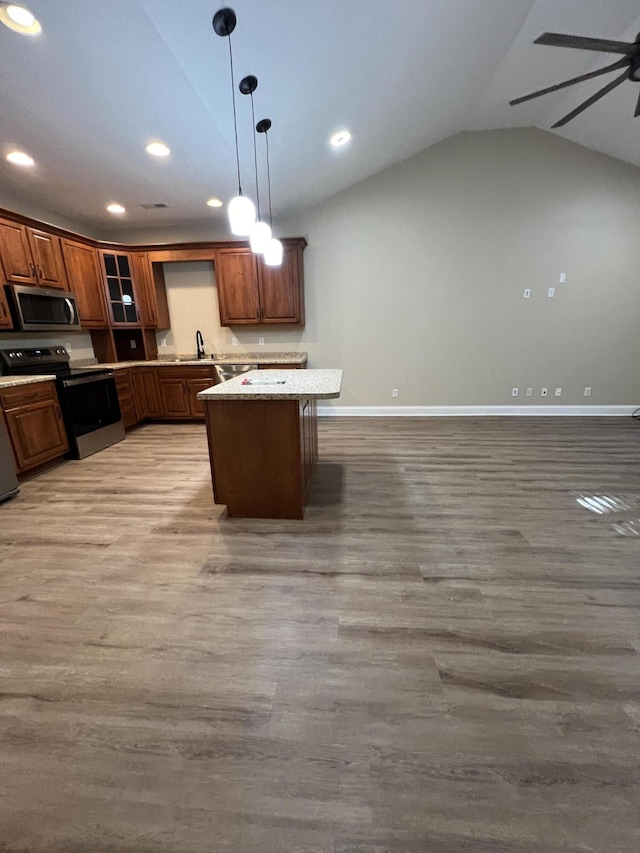 kitchen with vaulted ceiling, appliances with stainless steel finishes, sink, hanging light fixtures, and light stone counters