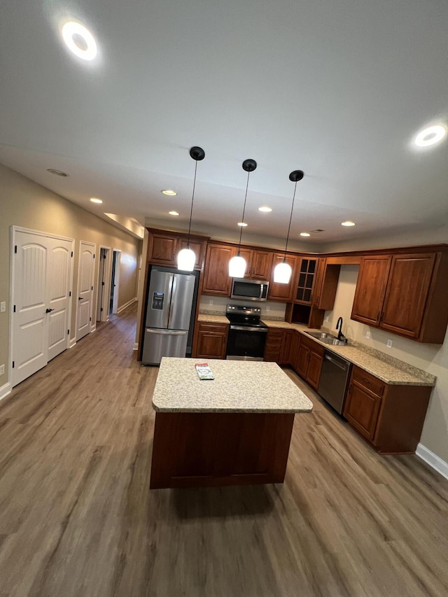 kitchen with pendant lighting, hardwood / wood-style floors, a center island, and appliances with stainless steel finishes