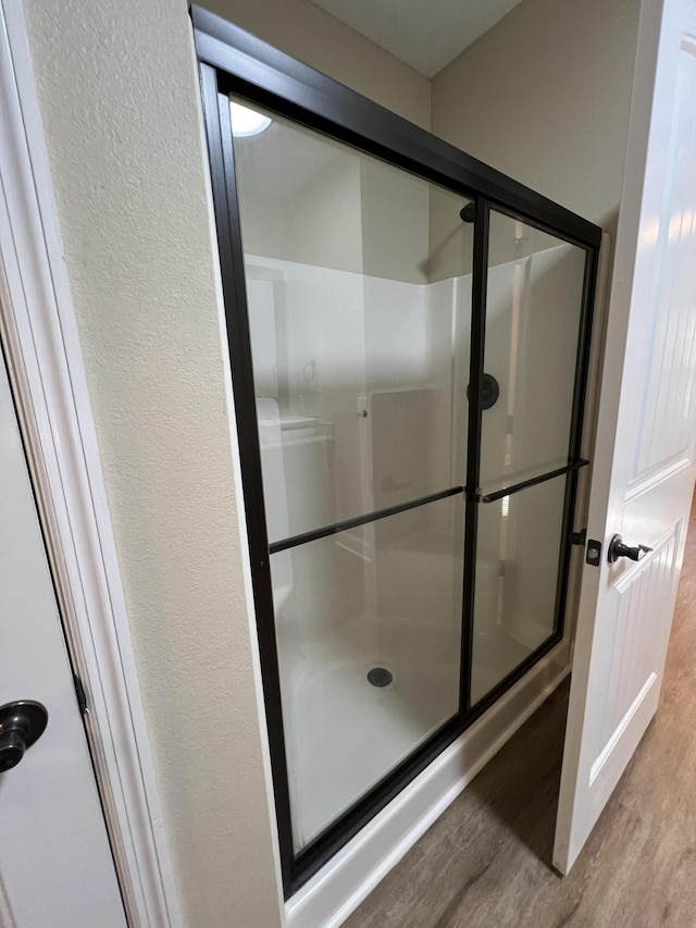 bathroom featuring hardwood / wood-style flooring and a shower with shower door