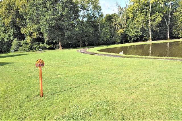 surrounding community with a water view and a lawn