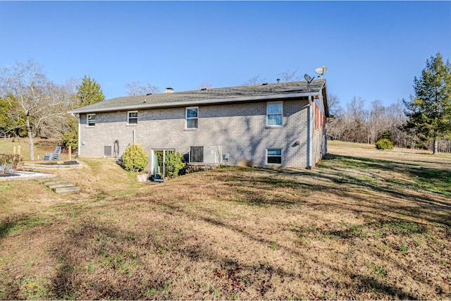 rear view of property featuring cooling unit and a lawn