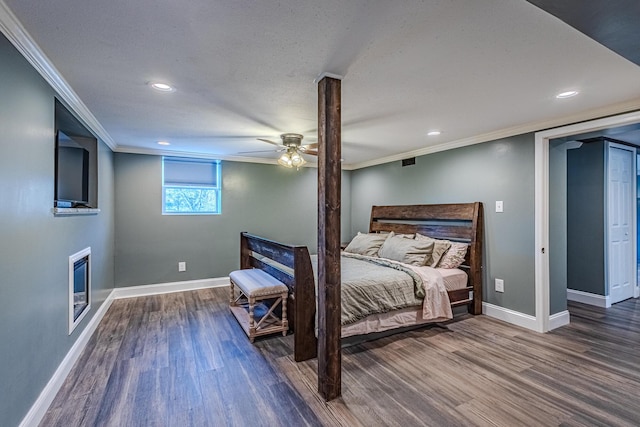 bedroom featuring crown molding, a fireplace, dark hardwood / wood-style floors, and ceiling fan