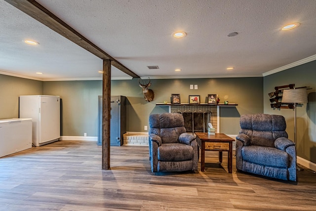 sitting room featuring ornamental molding, a textured ceiling, and light wood-type flooring