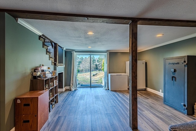 unfurnished living room featuring ornamental molding, a textured ceiling, and light hardwood / wood-style floors