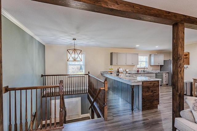 kitchen featuring pendant lighting, sink, dark wood-type flooring, light stone counters, and a kitchen bar