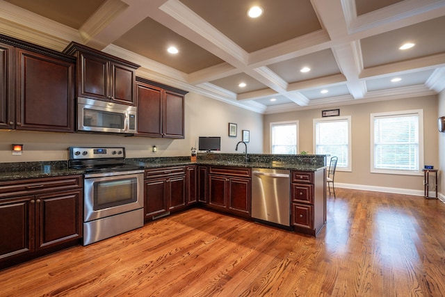 kitchen featuring stainless steel appliances, beamed ceiling, dark stone counters, and kitchen peninsula