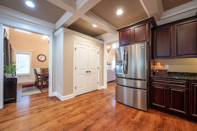 kitchen featuring ornamental molding, stainless steel fridge with ice dispenser, and dark stone counters