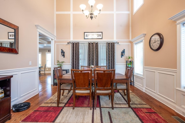 dining room with hardwood / wood-style flooring, a high ceiling, and a notable chandelier